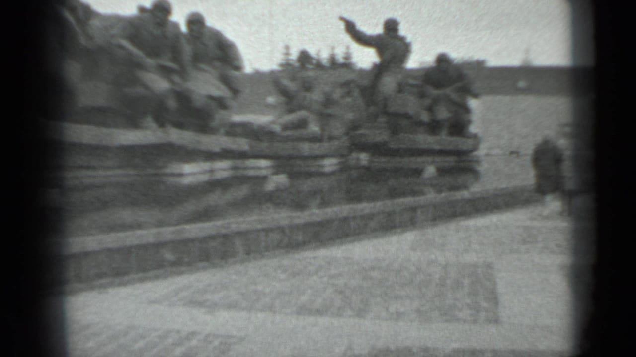 Distant visitors near a large soldier monument beside a paved plaza.