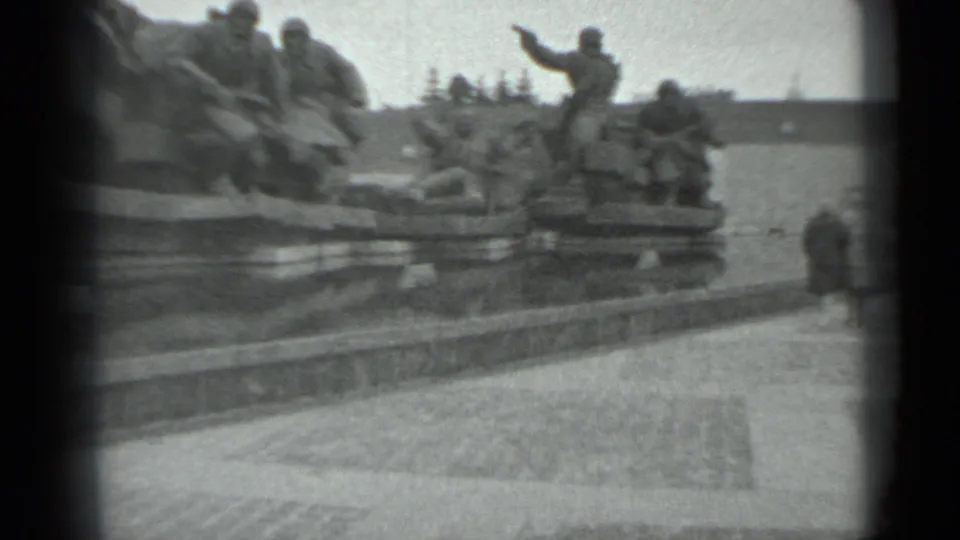 1983 Moscow home-movie frame showing visitors at a large sculpted soldier memorial in a public plaza.