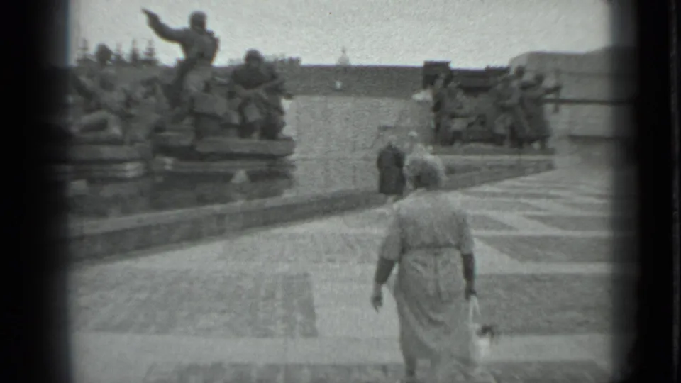 Rear view of a woman in a coat crossing the plaza toward sculpted soldiers at a Moscow memorial.