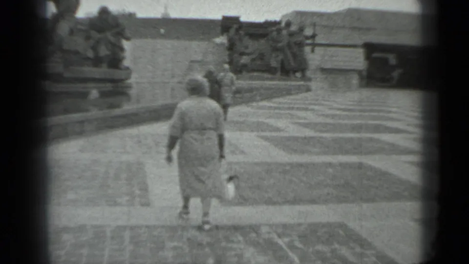 Woman walks on patterned plaza paving near the soldier memorial in 1983 Moscow home-movie footage.