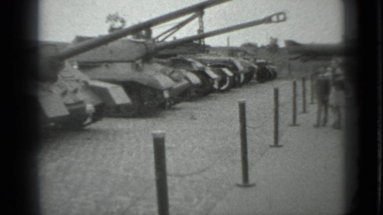 1983 Moscow frame with armored tanks displayed outdoors as civilians stand near the barrier at the edge of view.