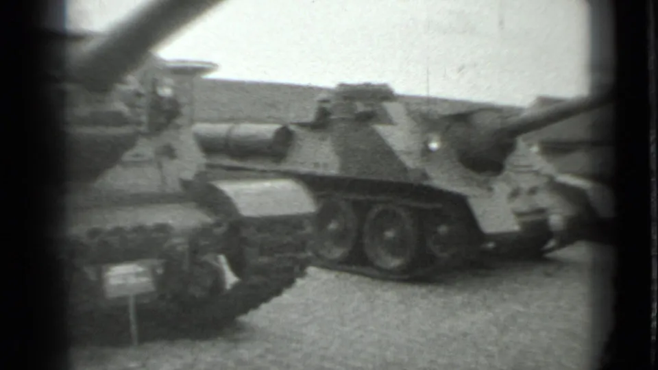 1983 Moscow 8mm frame showing Soviet-era armored vehicles on static display with tracks, turret shapes, and small placards visible.