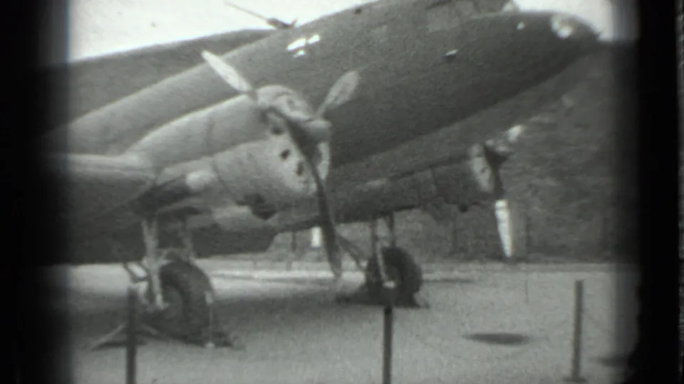 1983 Moscow 8mm frame showing a propeller-driven military aircraft on static display, including nose, engine, landing gear, and barriers.
