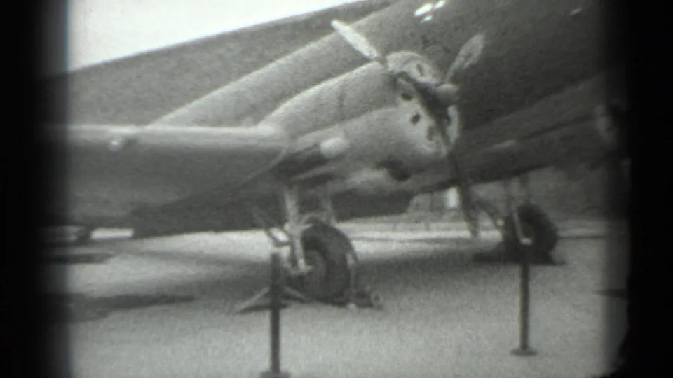 1983 Moscow 8mm frame showing a propeller-driven military aircraft on display behind stanchions and rope barriers.