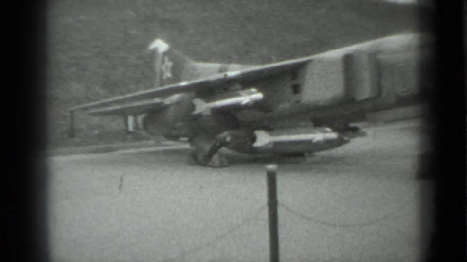 1983 Moscow 8mm frame showing the rear side of a military jet fighter on display behind rope barriers and stanchions.