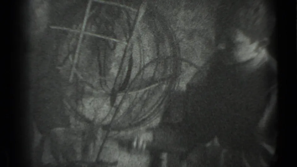 1983 Moscow 8mm frame showing a dim workshop-like interior with a partially seen person and indistinct metal or tool shapes.