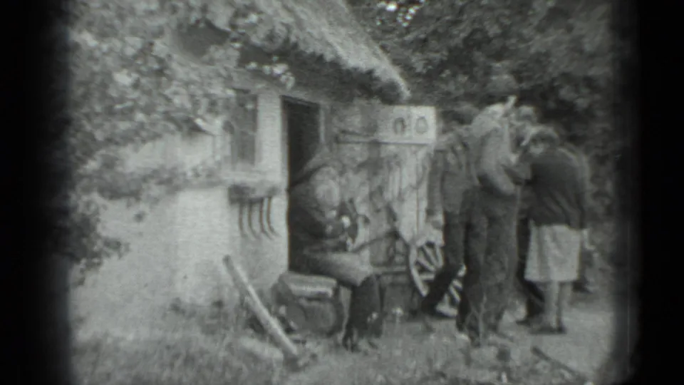 Home-movie frame from the 1983 Moscow-area clip showing visitors gathered tightly around a rustic horseshoe and wheel display.