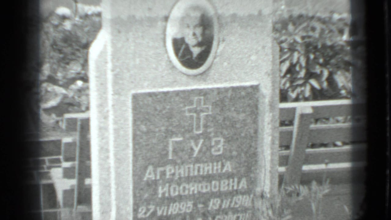 Close view of a Cyrillic gravestone with an oval portrait and cross motif.