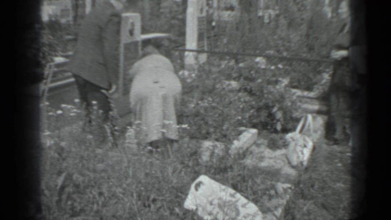 Older adults bend over a garden bed with bags and flowers around them.