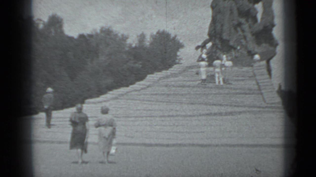 Several visitors in 1983 Moscow walk up wide stone steps toward a large sculptural monument in a landscaped setting.