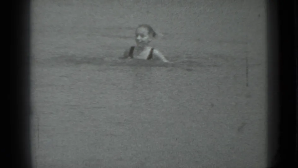 A young swimmer, likely a girl, is visible from the shoulders up in Moscow, Russia, 1983 lake footage with heavy 8mm grain.