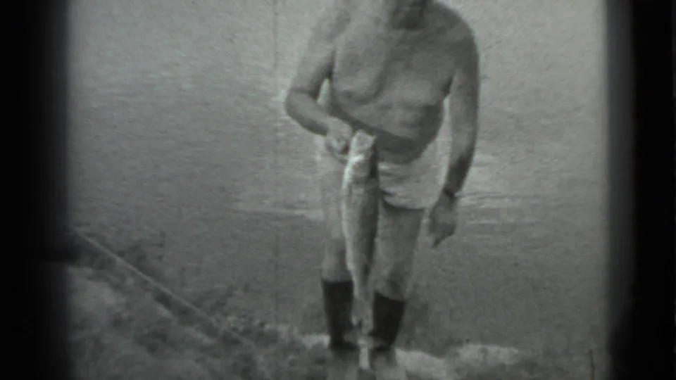 The man steps gingerly up from the riverbank in Moscow, holding a large fish in one hand as the water fills the background.