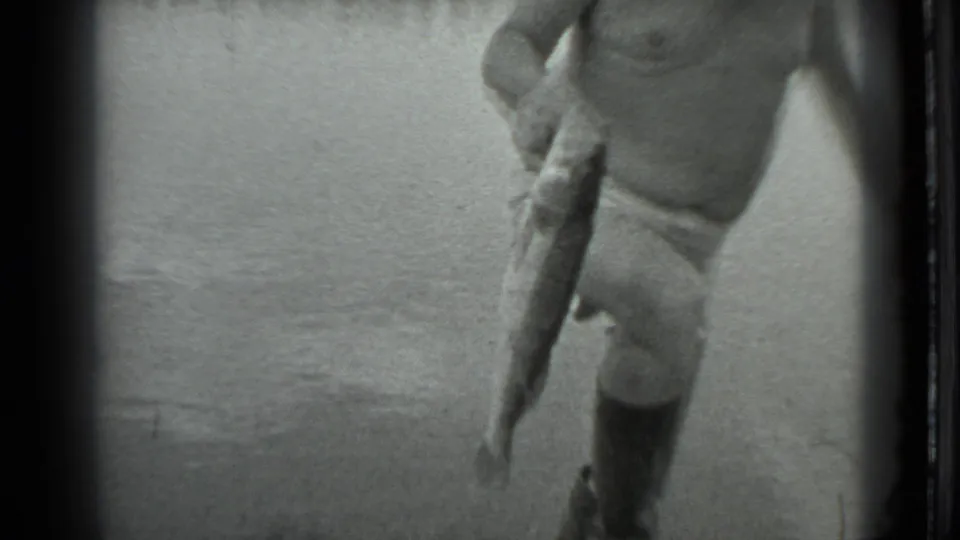The final frame shows the shirtless man leaning forward with the fish near the water, framed tightly by the handheld camera.