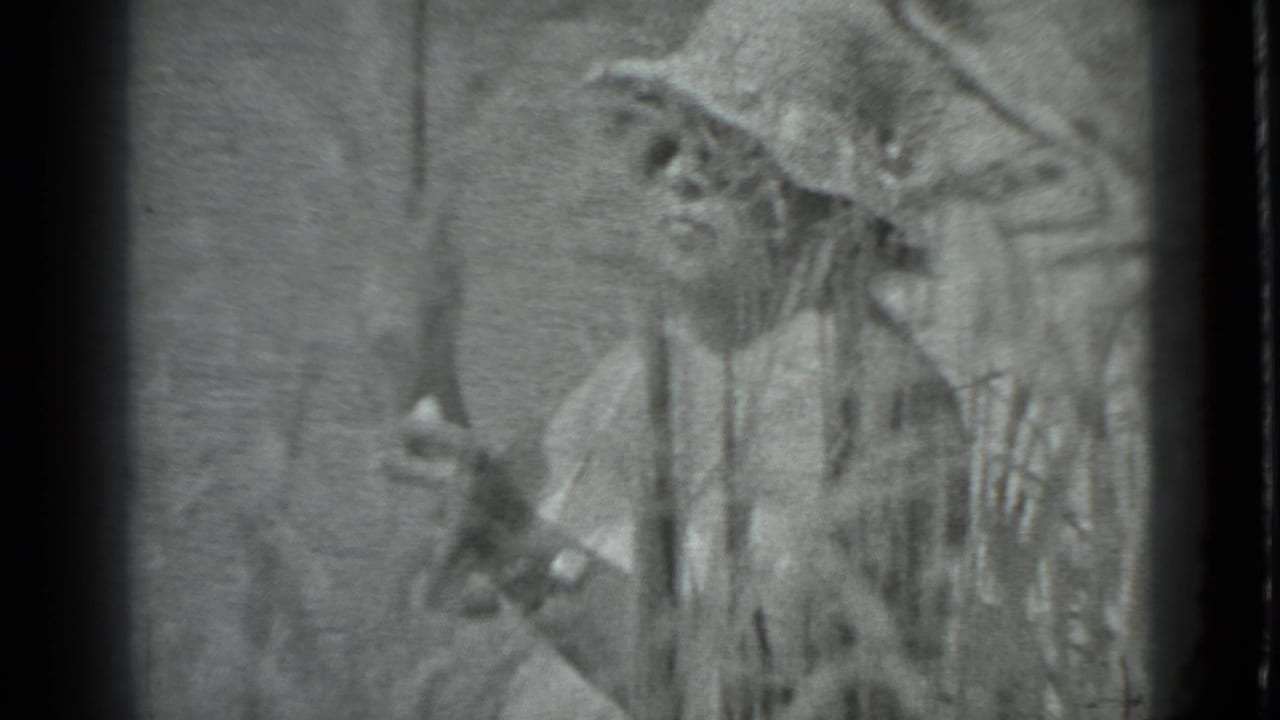 In 1983 Moscow home-movie footage, a person with a wide-brimmed hat stands partly obscured by reeds while holding a fishing rod near the river.