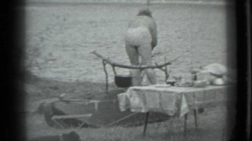 1983 Moscow campground frame showing a person from behind near a covered table, with camping gear and grass around them.