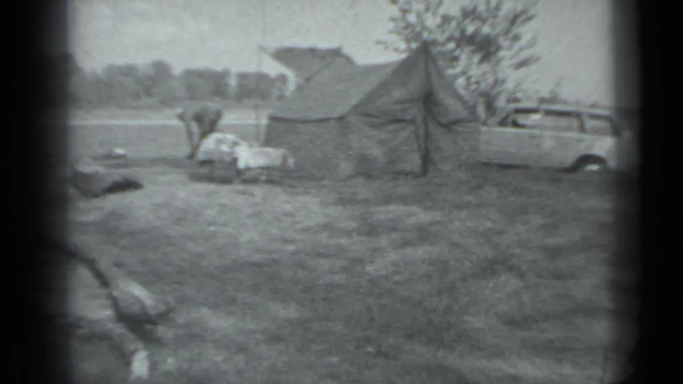 1983 Moscow campsite view with a canvas tent, a person by the gear, and a light-colored station wagon at frame right.