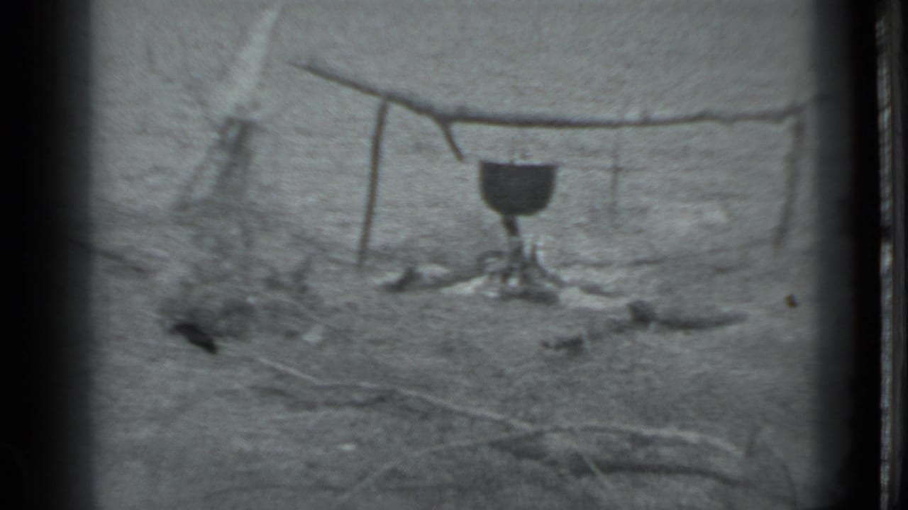 A pot hangs over a simple campfire setup in archival 8mm footage supplied as Moscow, Russia, 1983.