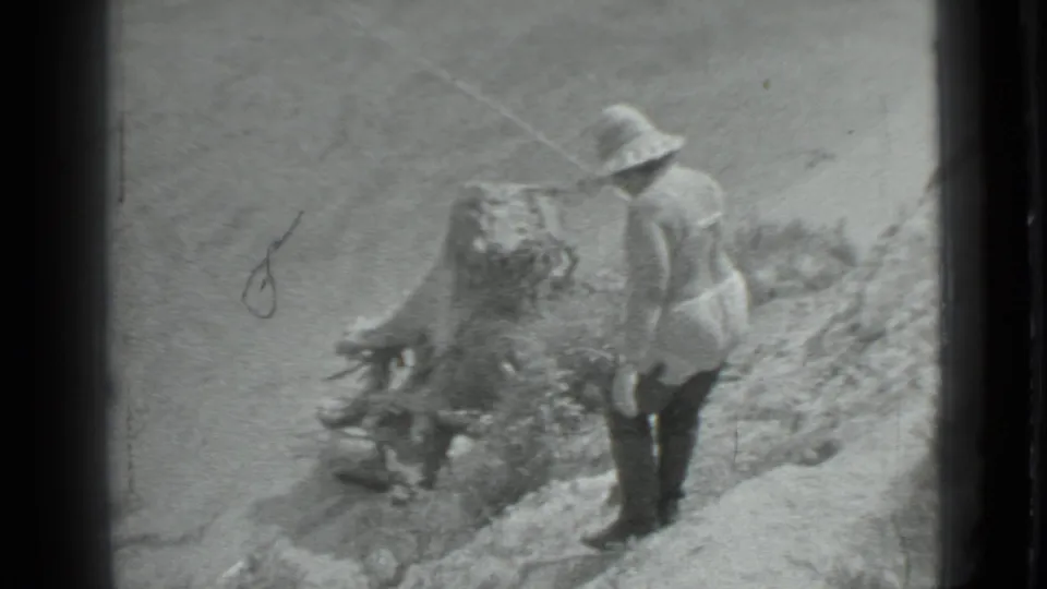An adult man in a brimmed hat stands on a rocky bank beside the river, with fishing gear visible in the 1983 Moscow clip.