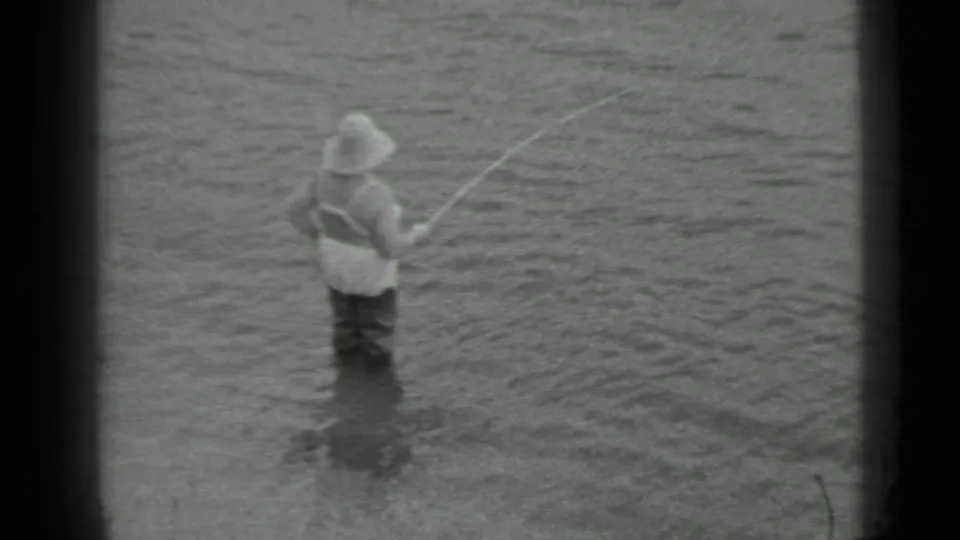The angler remains in the river, holding his rod as ripples spread around his legs in the 1983 Moscow footage.