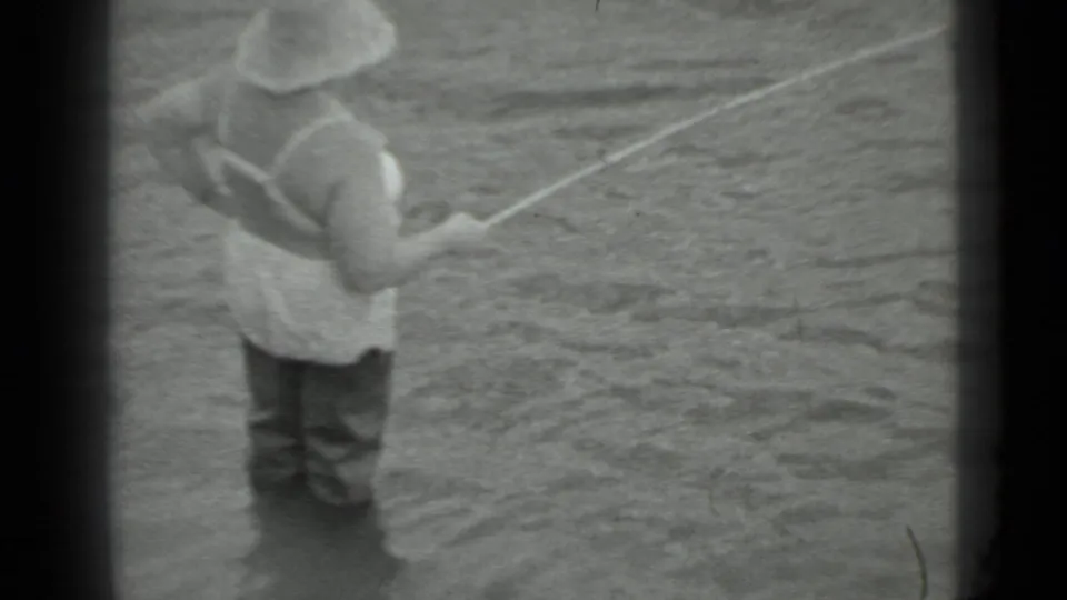 1983 Moscow-area 8mm frame of a woman in shallow river water holding a fishing line near a quiet bank.