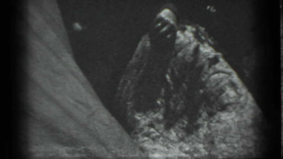 Soft 8mm close-up in the Moscow 1983 footage showing a rough dark surface next to a pale sloping shape, with heavy grain.