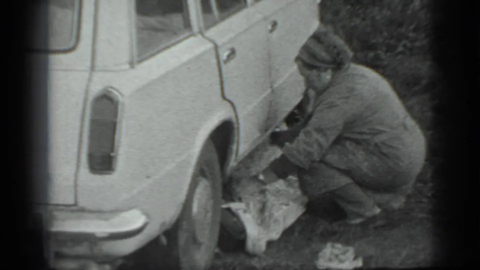 At the end of the Moscow 1983 clip, the crouching man reaches near the rear wheel while a cloth or bag lies below.