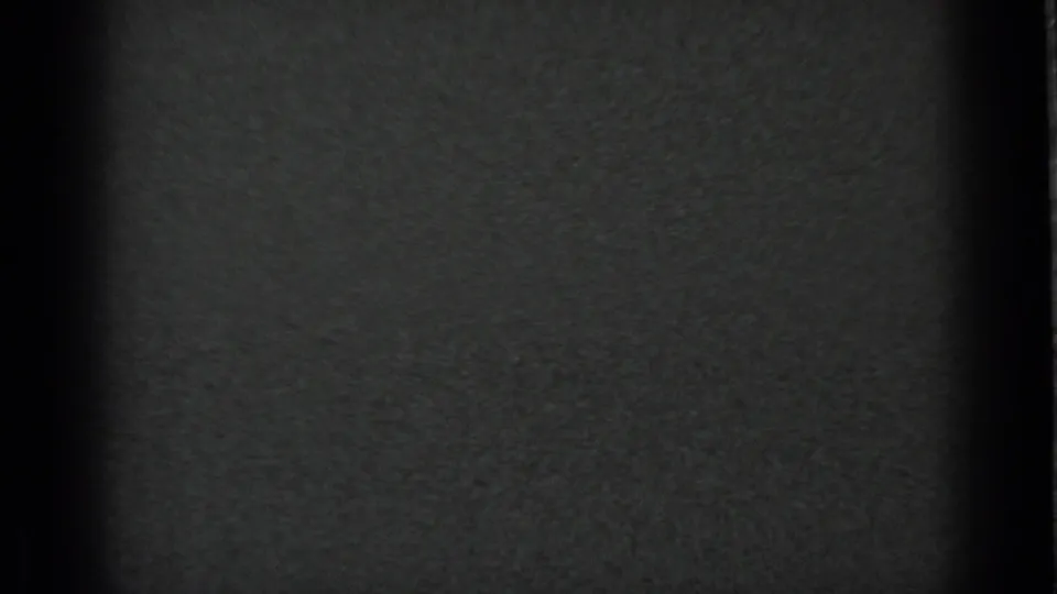 End frame from the black-and-white 8mm clip, largely dark with visible film grain and no identifiable campsite details.