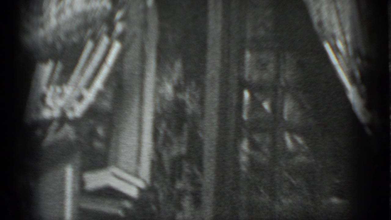 Black-and-white 8mm frame from Moscow, 1983, with a woman in striped pants moving past a doorway inside a private room.