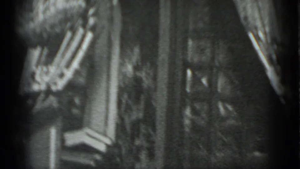 Black-and-white 8mm frame from Moscow, 1983, with a woman in striped pants moving past a doorway inside a private room.