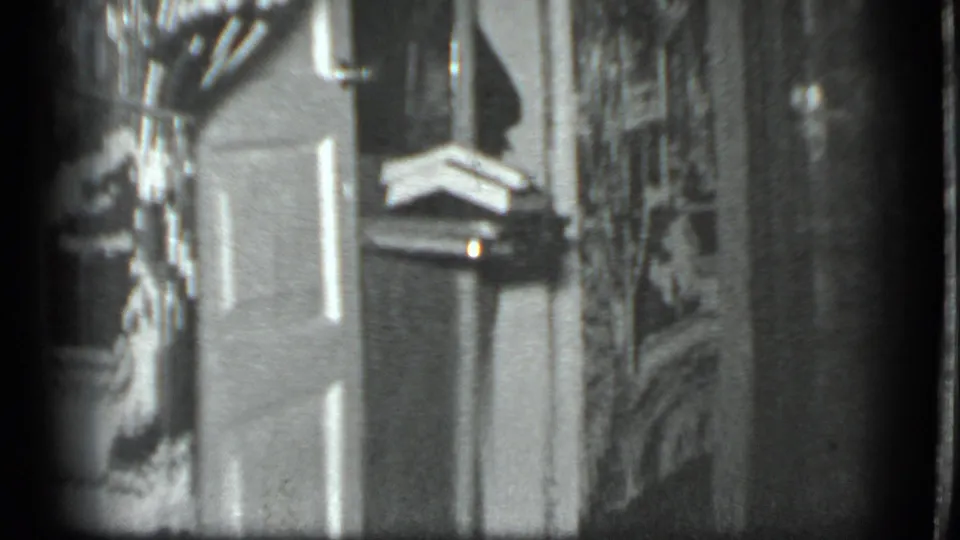 1983 Moscow black-and-white 8mm frame showing a paneled door, shelves and household items in a private interior.