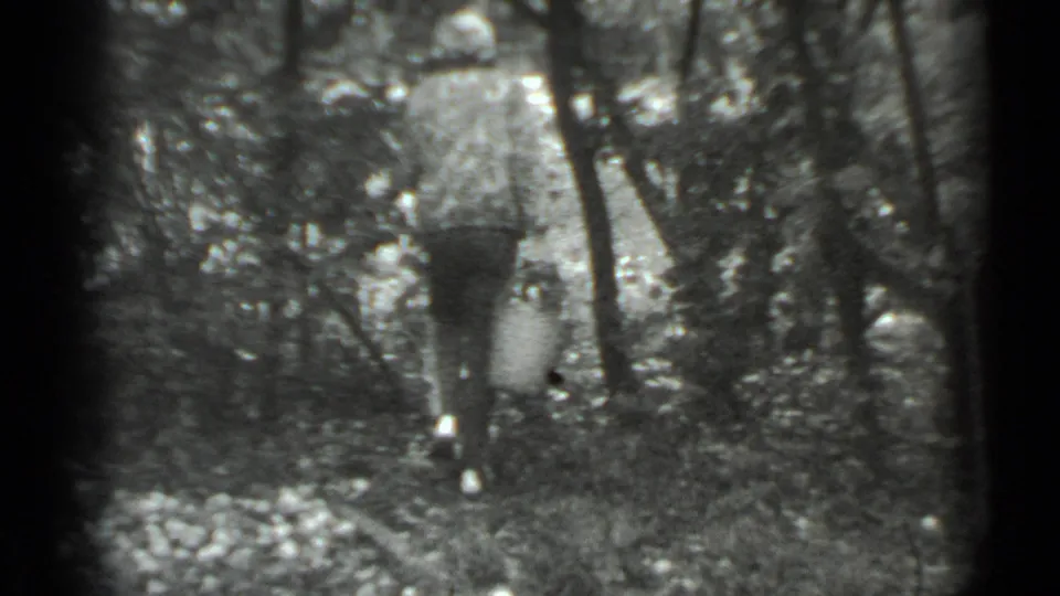 The woman walks away into the wooded Moscow area, her patterned jacket and headscarf visible in soft 8mm focus.