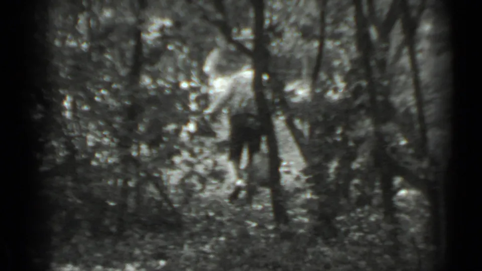 The woman remains visible between trees, holding a bucket in a wooded Moscow setting from the 1983 home movie.