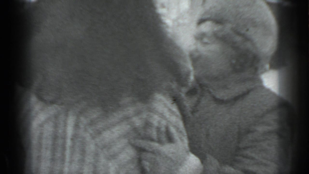 A man in a fur hat faces a woman in a light winter coat during an embrace.