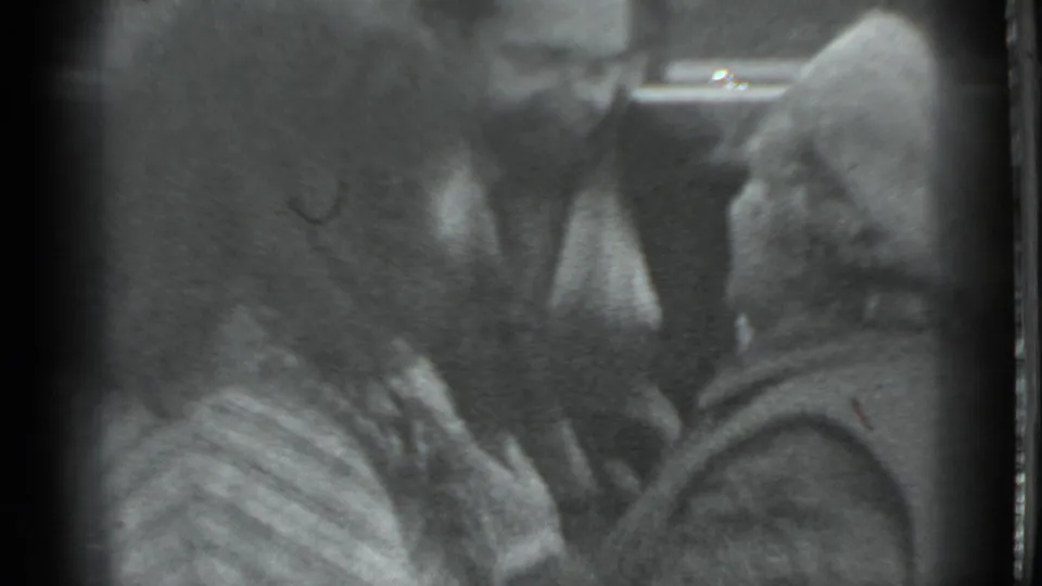 Three adults in heavy winter clothing gather closely in grainy Moscow 1983 home-movie footage.