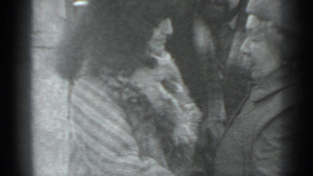 A woman and man face each other closely while another adult is partly visible between them.