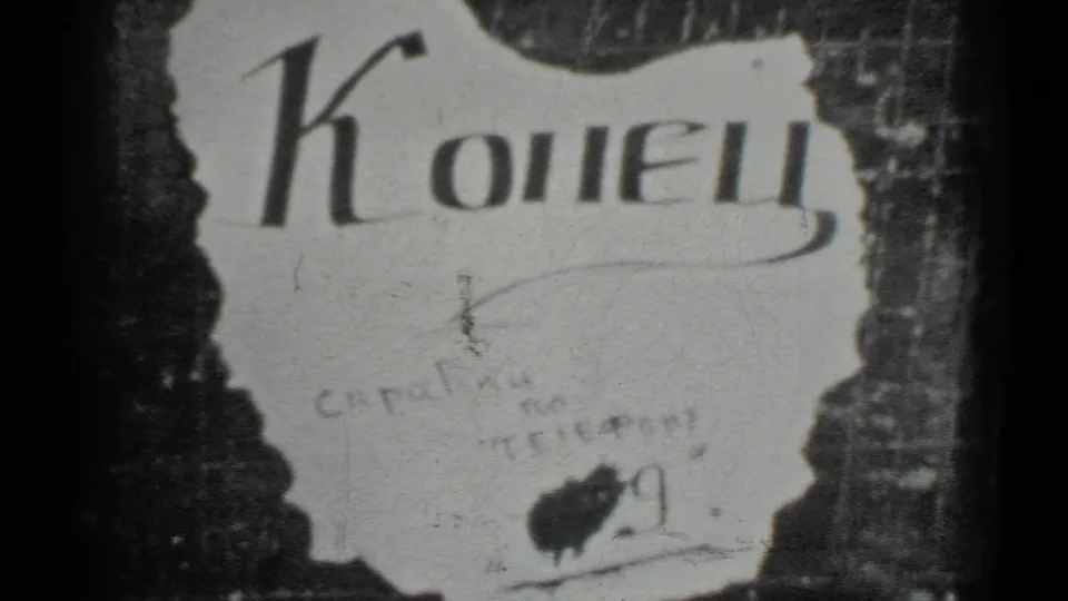 Moscow 1983 8mm frame showing the torn white "Конец" sign, faint handwritten marks, and a dark blot on textured backing.