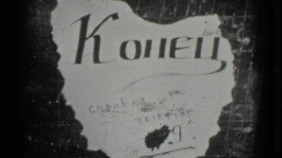 Moscow 1983 8mm close-up of the "Конец" end sign with torn edges, dark backing, gate shadow, grain, and scratches.