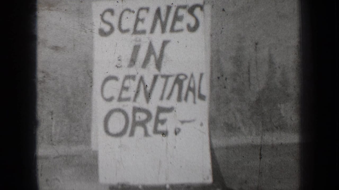 Handwritten sign reading SCENES IN CENTRAL ORE. outdoors on black-and-white film.