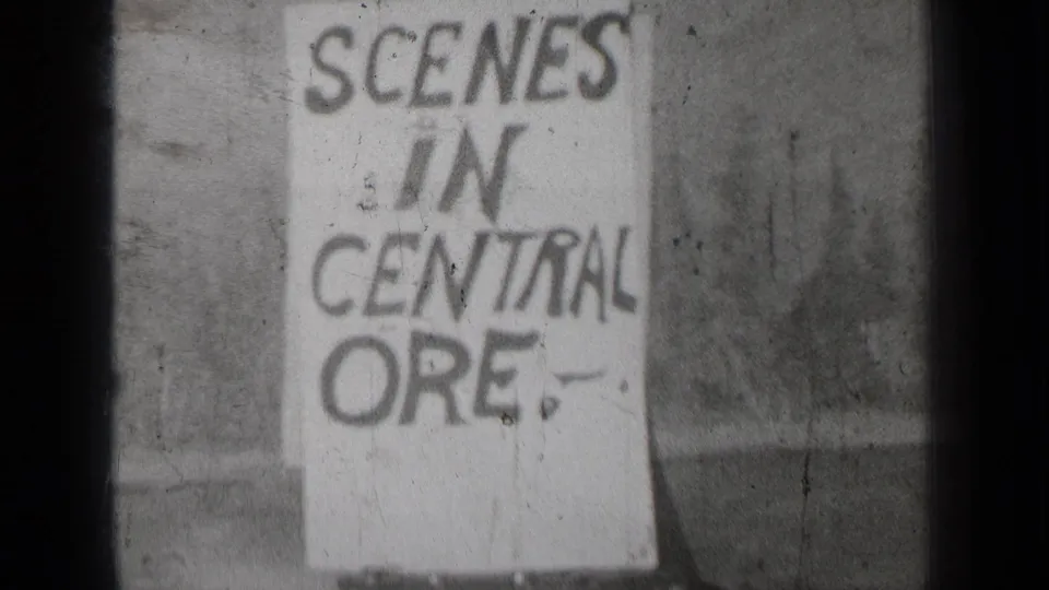 1937 Bend, Oregon 8mm frame with a handmade sign reading SCENES IN CENTRAL ORE. against a soft outdoor background.