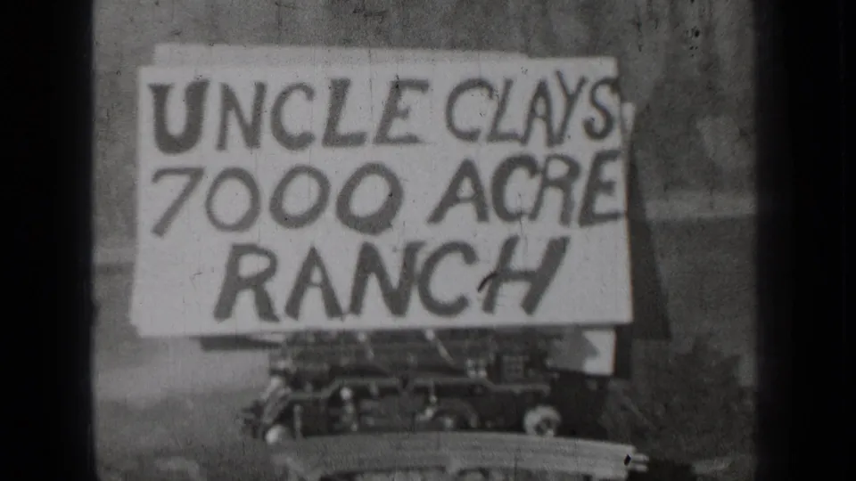 1937 Bend, Oregon 8mm frame showing a handmade Uncle Clays 7000 Acre Ranch sign with part of a vehicle below.