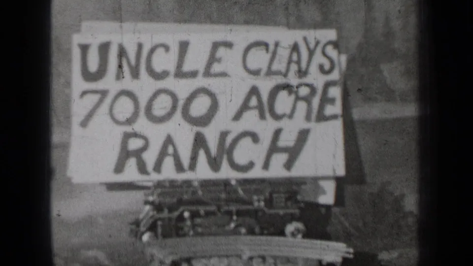 1937 Bend, Oregon 8mm frame showing a hand-lettered Uncle Clays 7000 Acre Ranch sign in soft black-and-white focus.