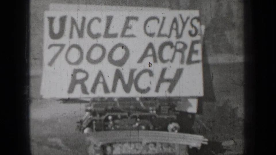 Final 1937 Bend, Oregon frame showing the Uncle Clays 7000 Acre Ranch sign against a plain backdrop in worn 8mm texture.