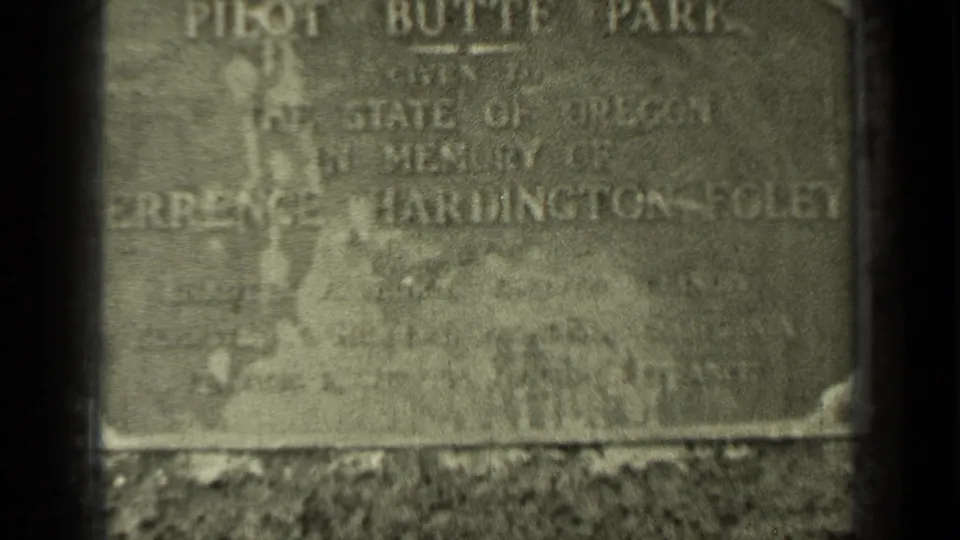 Close 8mm view of the Pilot Butte Park engraved stone marker in Bend, Oregon, with weathered lettering and surrounding grass.