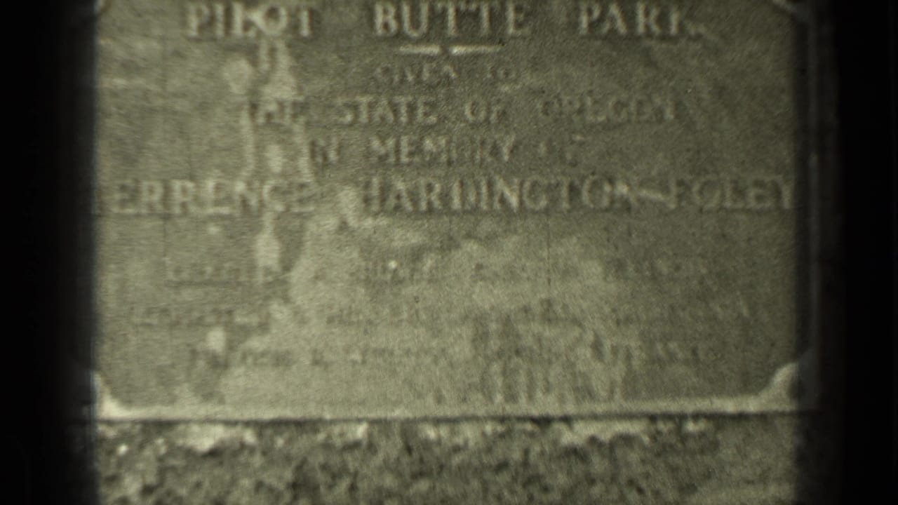 Weathered metal plaque at Pilot Butte Park, partly soft and framed by dark film edges.