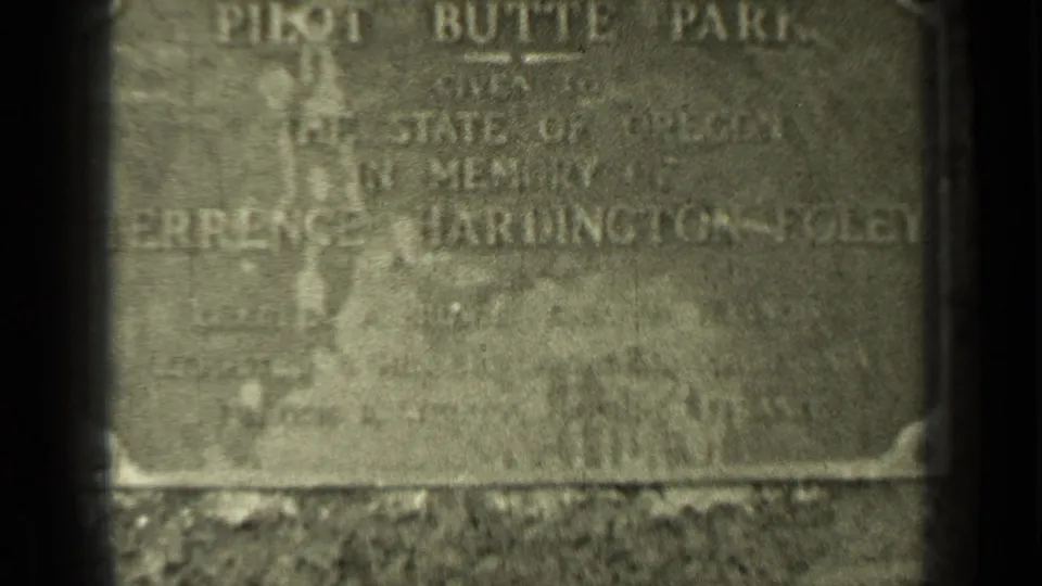 Close 1937 Bend, Oregon 8mm view of a weathered Pilot Butte Park memorial plaque with softened inscription and dark frame edges.
