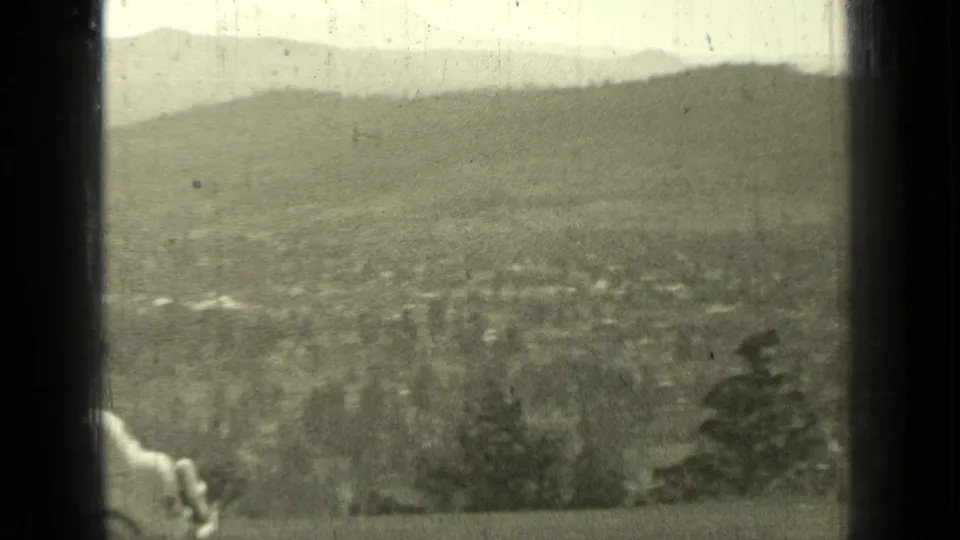 1937 Bend, Oregon home-movie frame showing a hazy valley and hills through dark film borders, with a partial light shape at the left edge.
