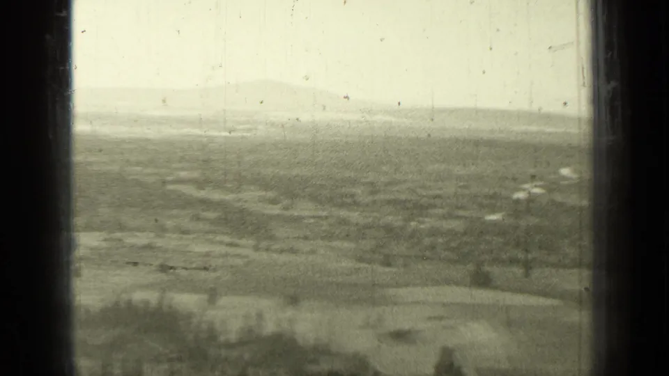 1937 Bend, Oregon home-movie frame showing open farmland, scattered trees, distant hills, and dark window-like borders.