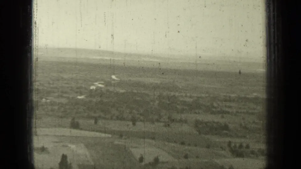 Archival 8mm view near Bend, Oregon, with farmland and low hills visible through a dark divided frame.