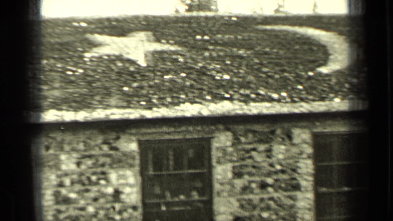 Close view of the stone house roof with a painted crescent or moon shape above a window.