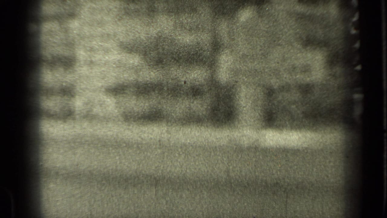 Soft black-and-white 8mm frame looking through a window toward an indistinct residential street in Bend, Oregon.